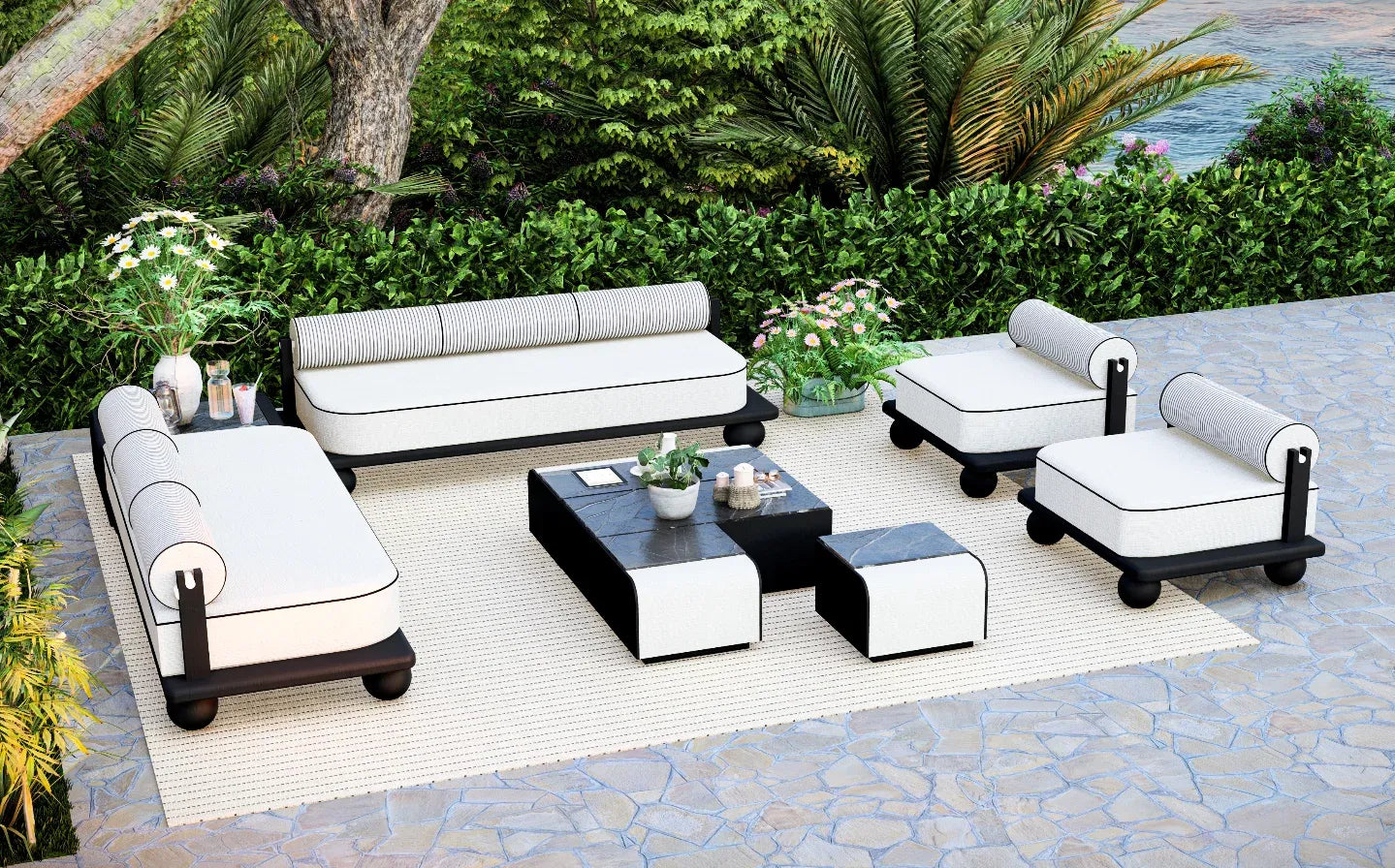 Outdoor patio furniture set with white cushions and black frames on stone patio.