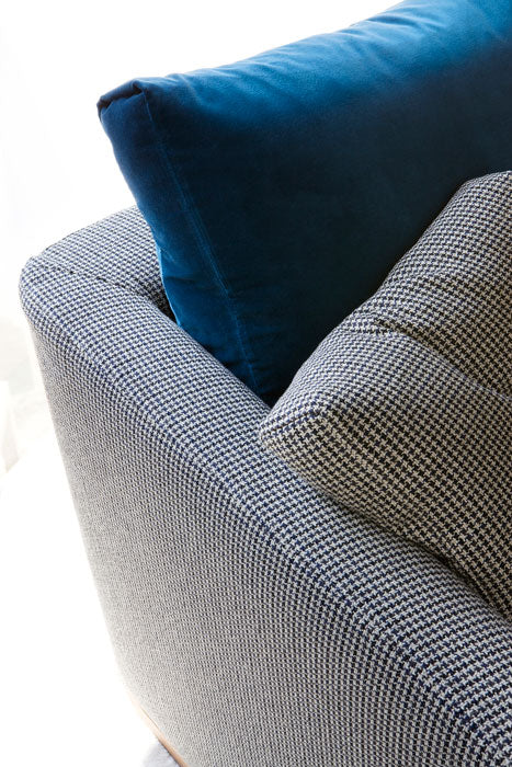 Close-up view of sofa with blue velvet and houndstooth cushions