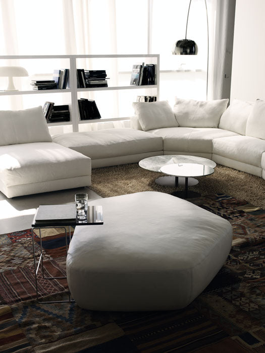 White modular sofa, ottoman, round coffee table, shelving, floor lamp, rug
