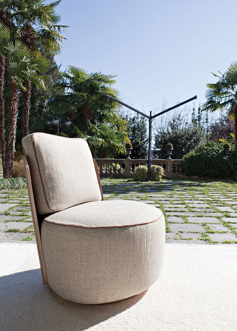 Outdoor view of beige upholstered round armchair on white rug