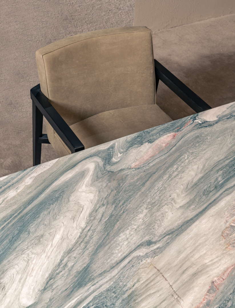 Overhead view of dining chair and marble table top. Dining chair with beige upholstery and black wood frame. 
