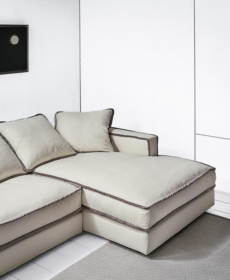  Close-up of a modern white sectional sofa with gray trim in a minimalist living room.
