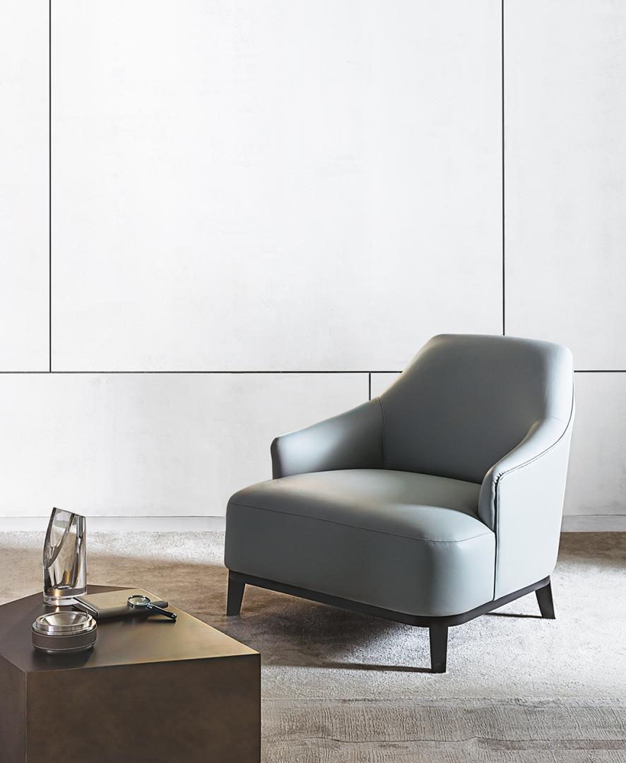 Modern gray leather Arne armchair with dark metal side table in a stylish living room, showcasing contemporary design and luxury furniture