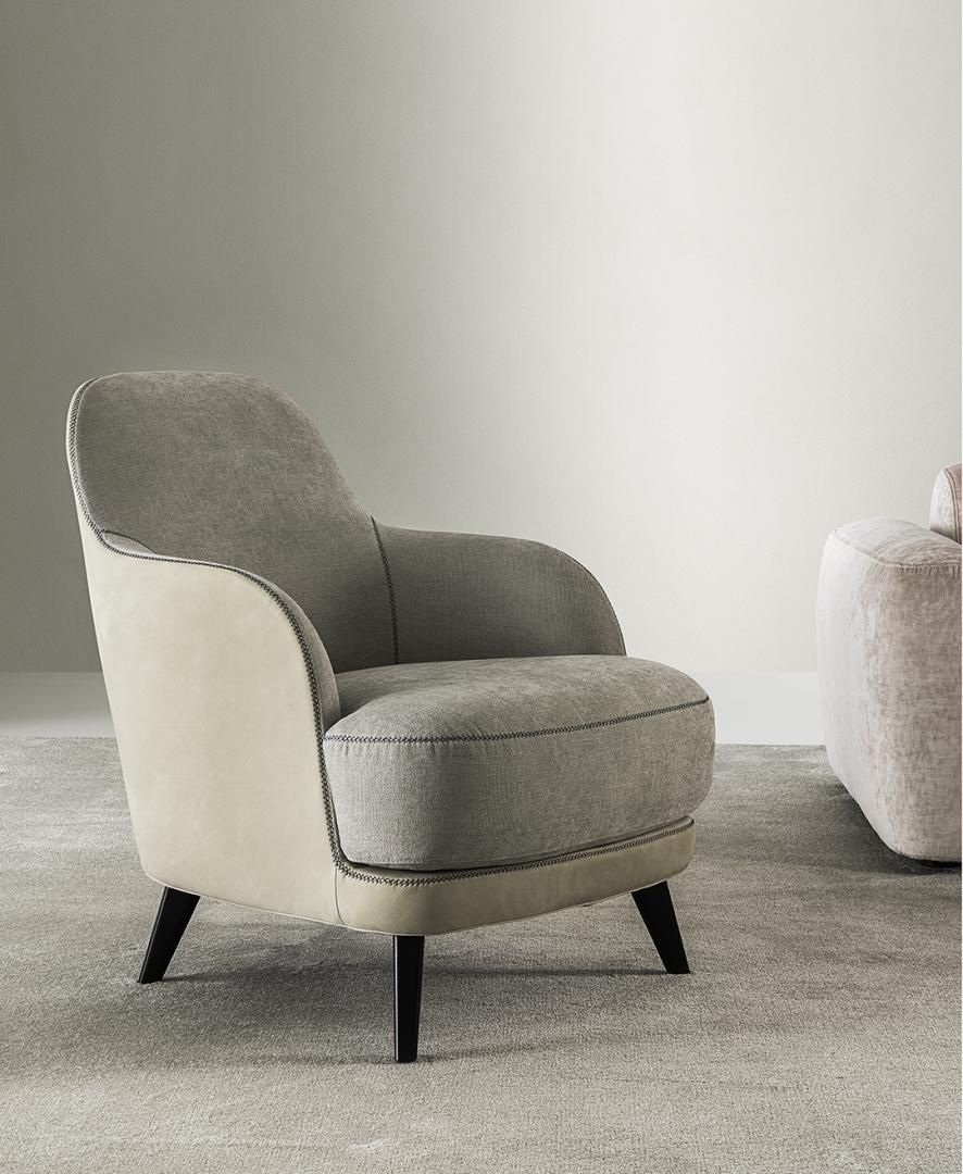  Interior of a living room featuring the Liz Armchair by Casamilano, showcasing its two-tone upholstery and sleek design