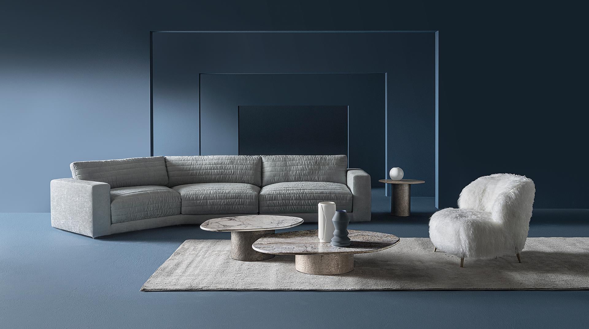  Interior with Casamilano Dhora Slim armchair, gray sofa, white accent chair, marble coffee tables, and blue accents. Modern living room design
