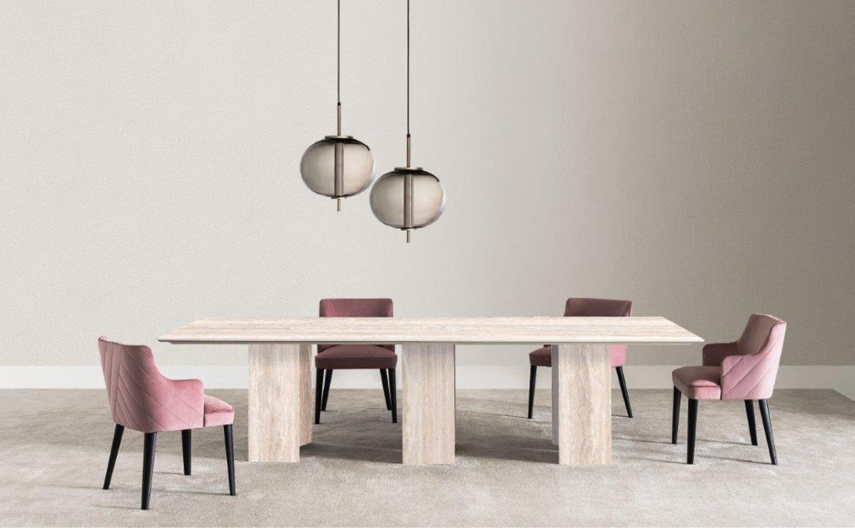 A modern dining room featuring a Casamilano Karl dining table, velvet chairs, and spherical pendant lights.