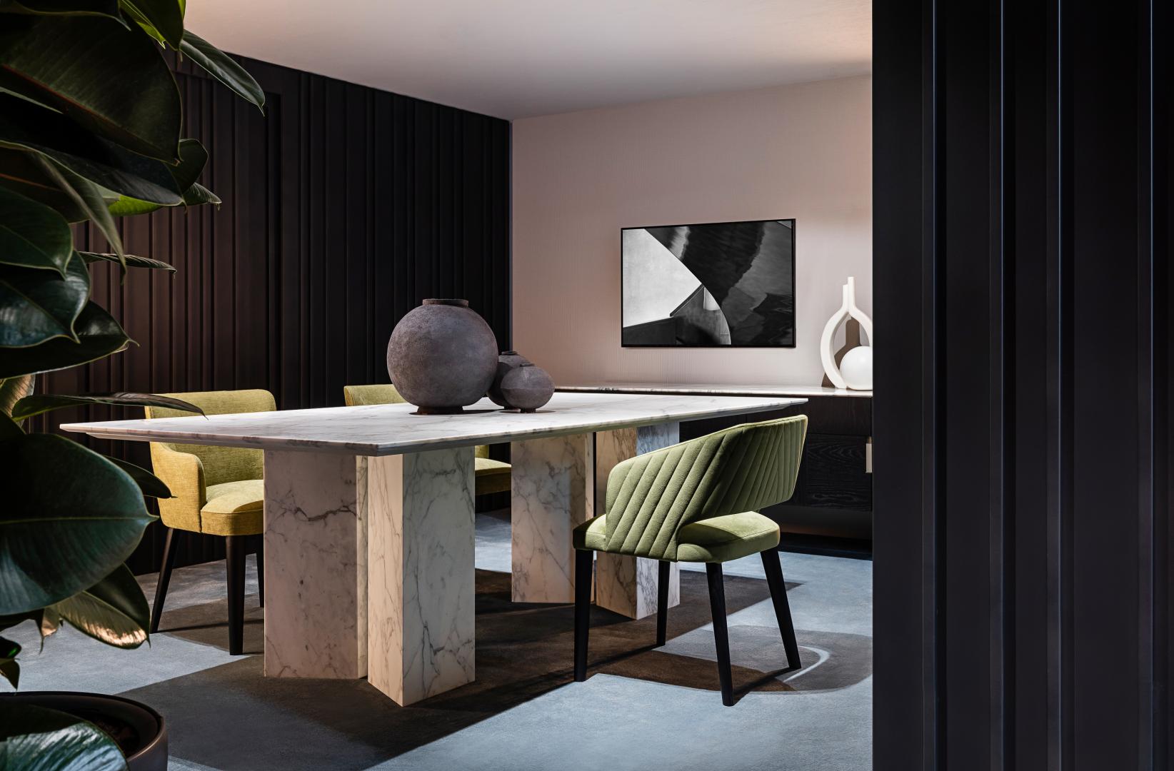 Modern dining room featuring a Casamilano Karl marble table and upholstered chairs in green and yellow velvet.