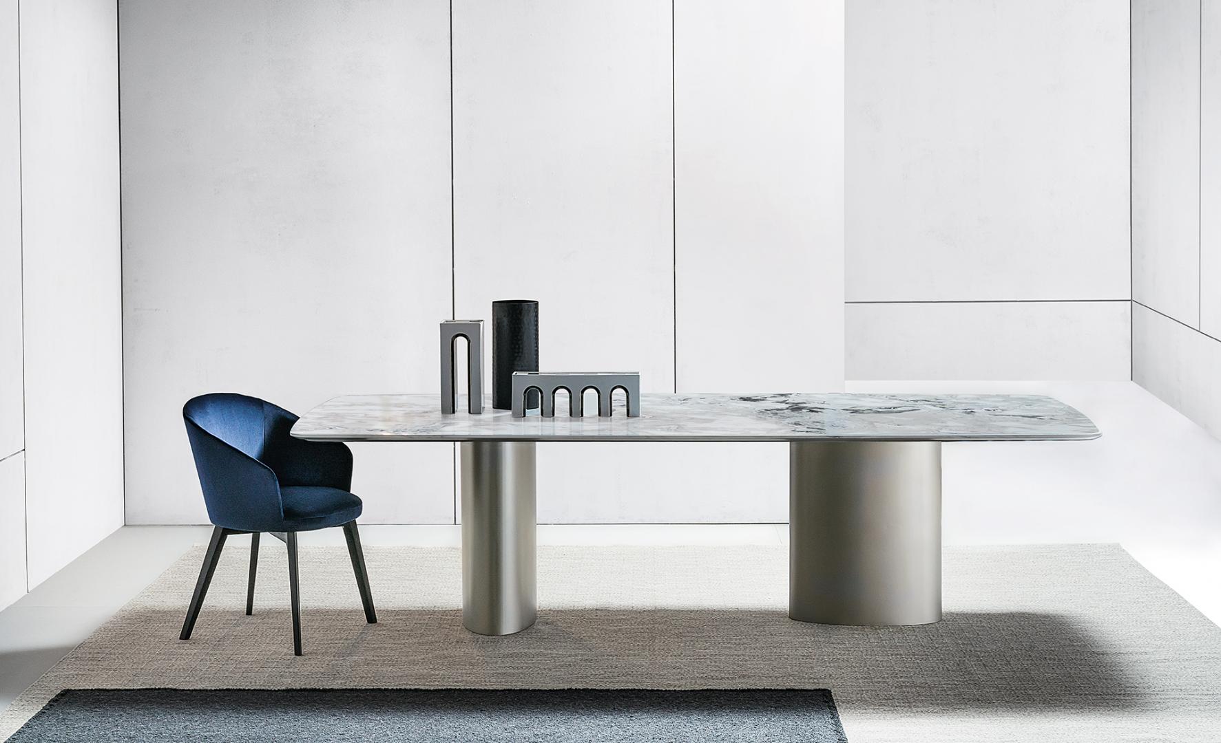 Interior of a modern dining room featuring a marble table, blue velvet Casamilano Shirley chair, and stylish decor, showcasing luxury and contemporary design