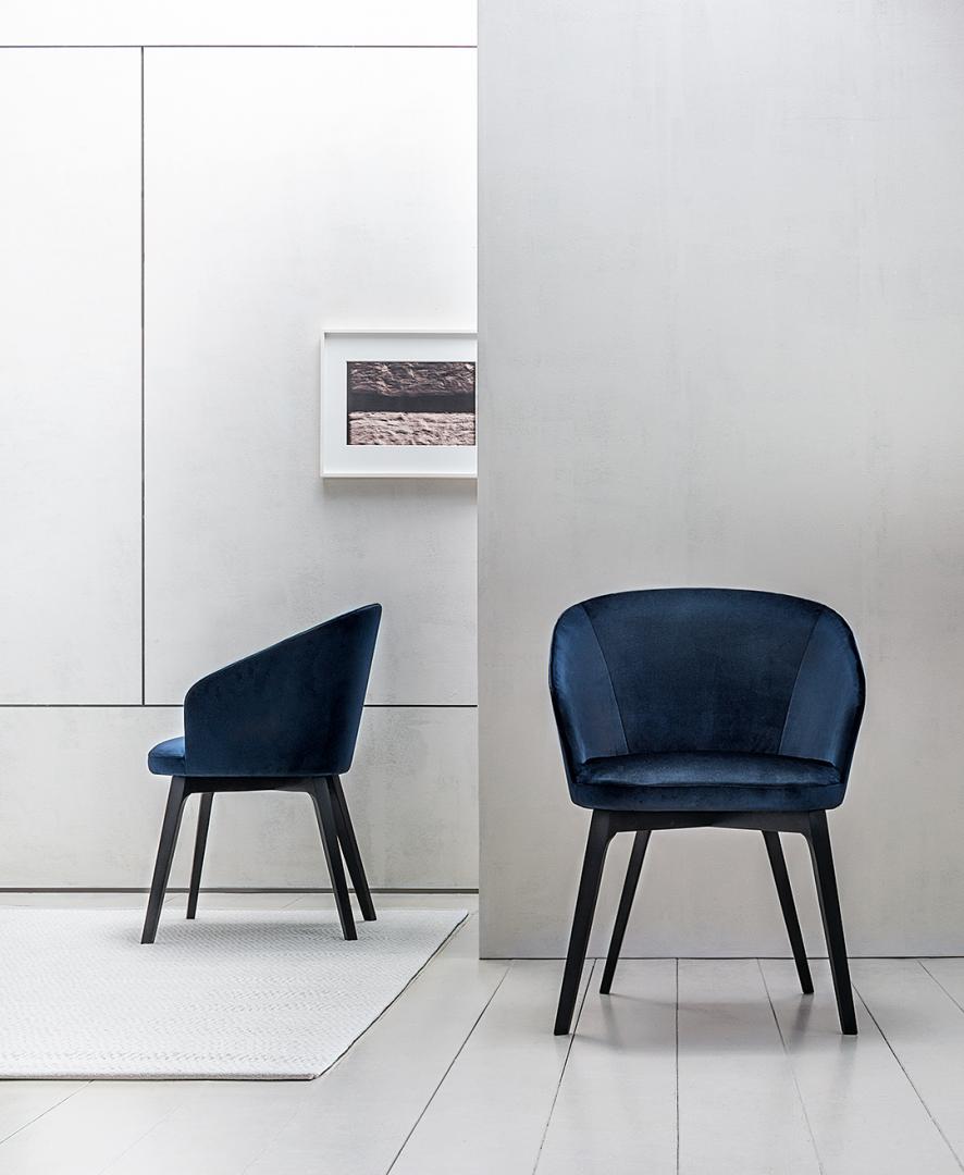 Elegant navy blue velvet Shirley dining chairs with black wooden legs in a minimalist room setting