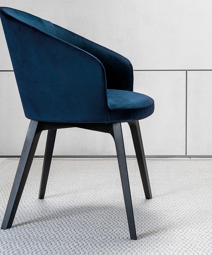 Luxurious blue velvet Shirley dining chair with dark wood legs by Casamilano adds a touch of modern elegance to any dining or living space