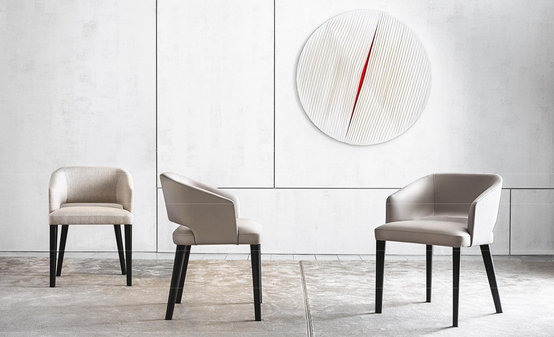 Modern dining chairs with light gray upholstery and black legs accent a minimalist dining space with stylish wall art