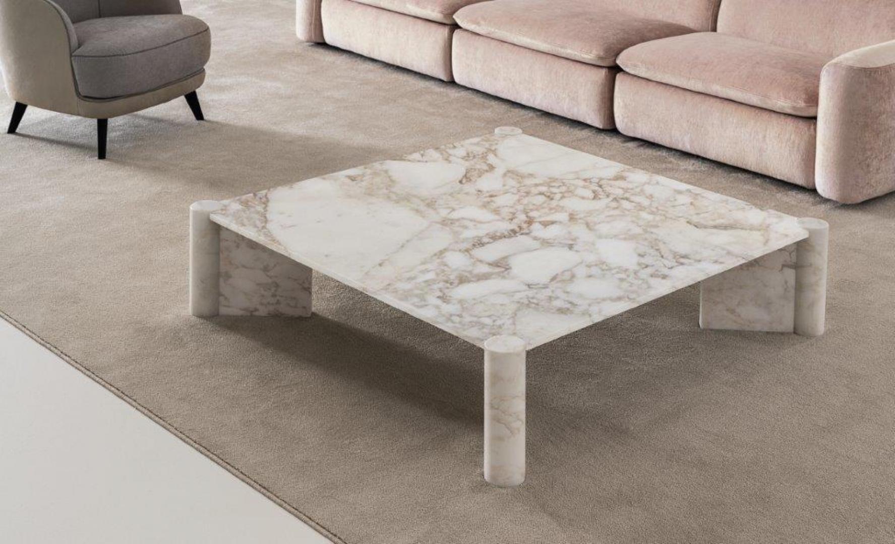  Interior of a modern living room featuring a Casamilano Petra marble coffee table, pink sofa, and gray armchair. Contemporary design and home decor
