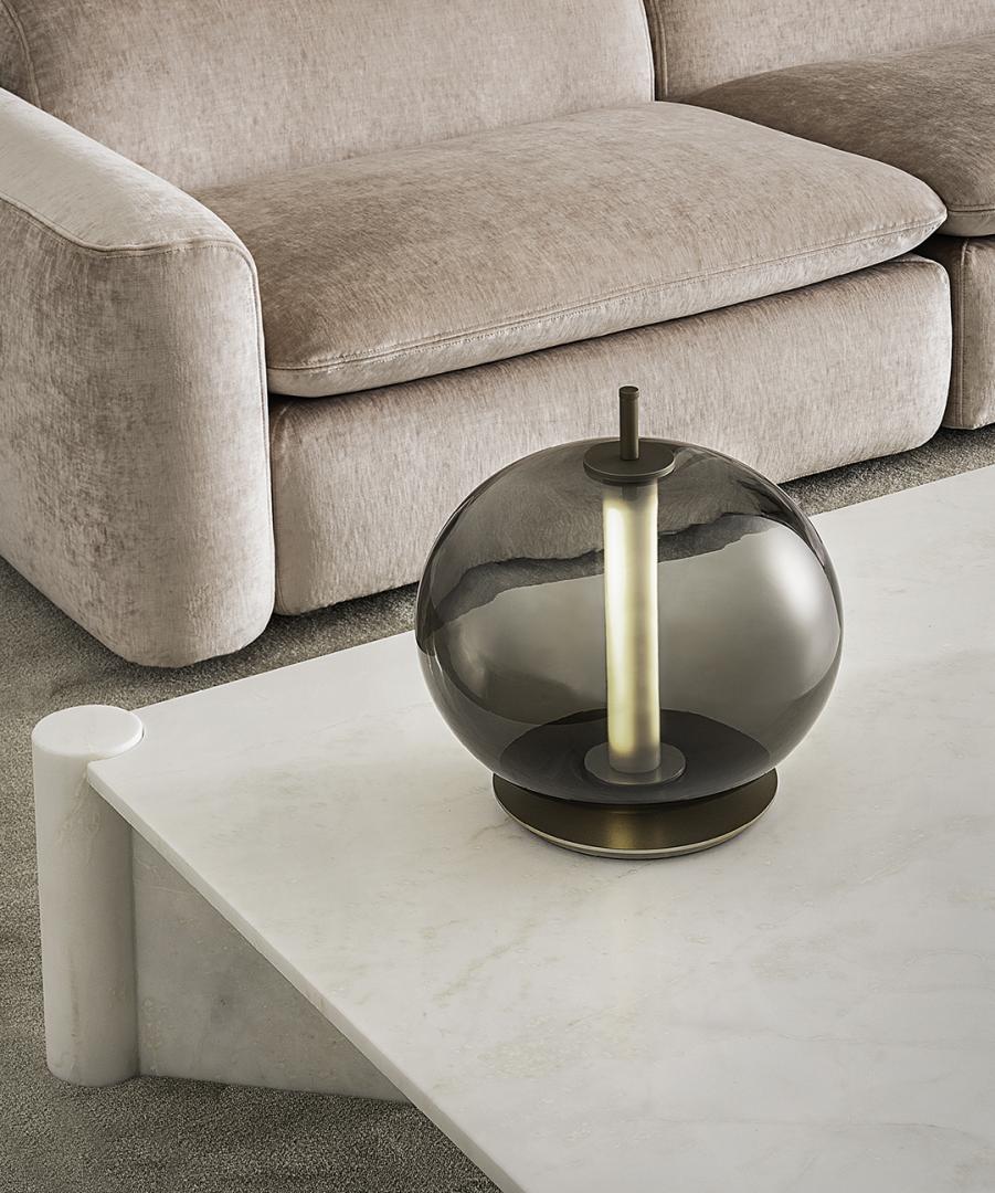  Interior of a stylish living room featuring a beige sofa, marble Petra coffee table, and glass orb lamp by Casamilano.