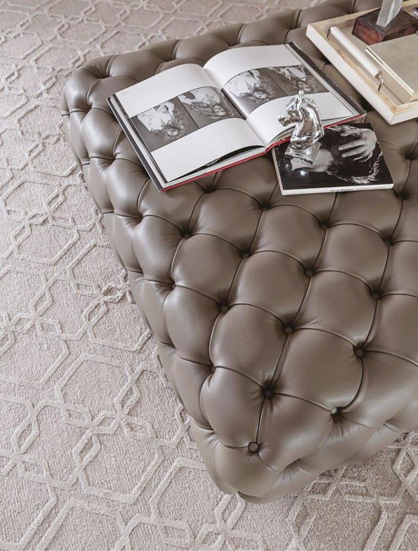 High-angle view of a Casamilano Hyatt 120 taupe leather tufted ottoman in a luxury living room.