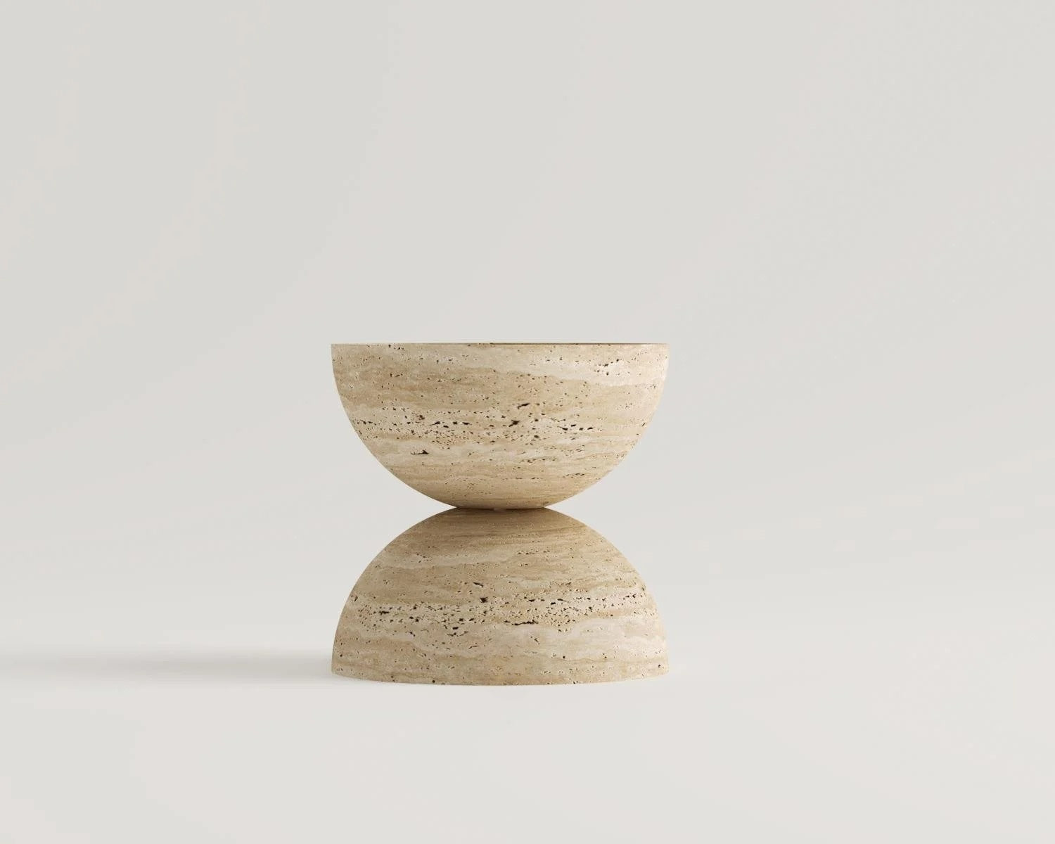 Studio shot of hourglass-shaped travertine stone decor sculpture on white background