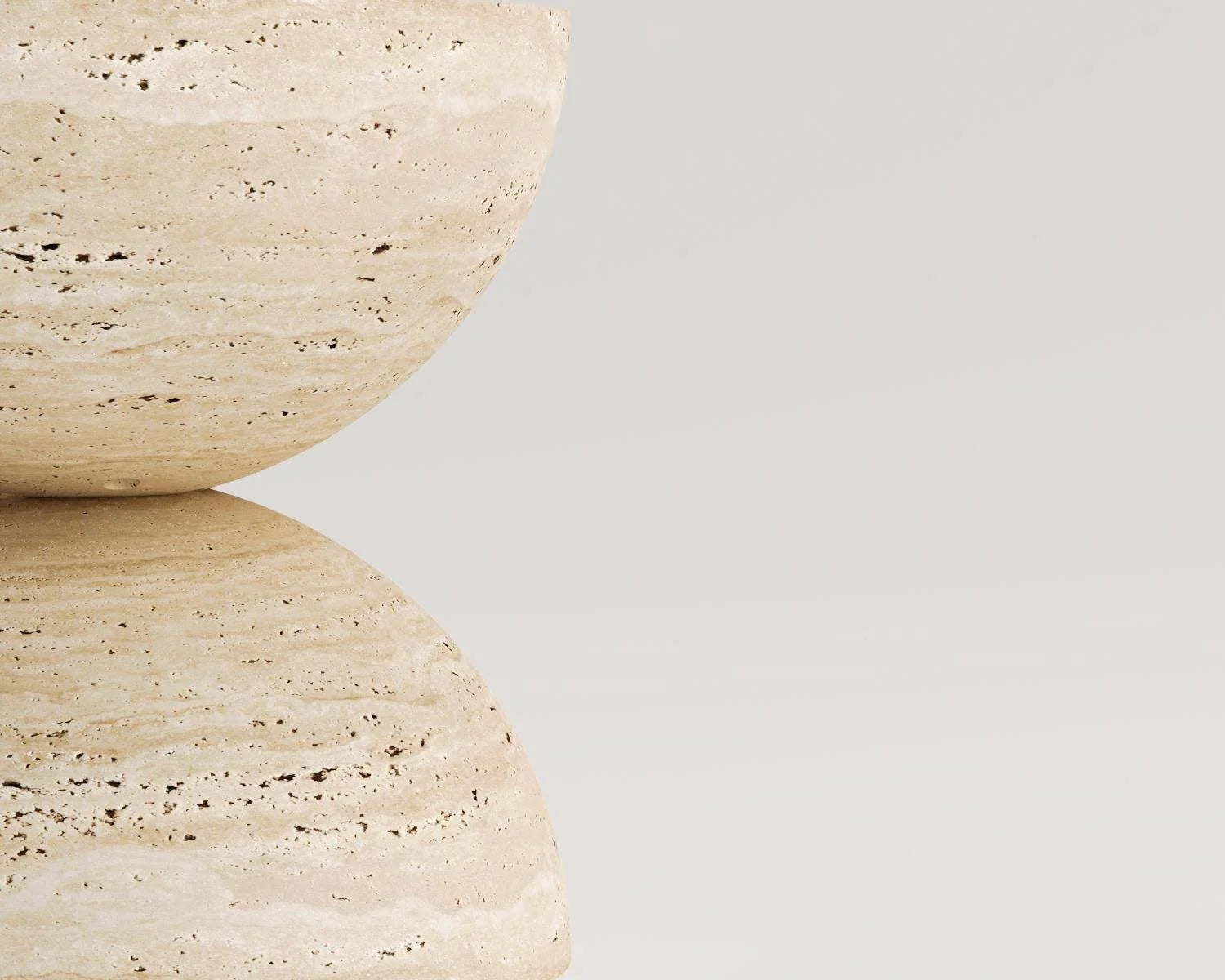Two stacked beige travertine bowls sculpture against white background