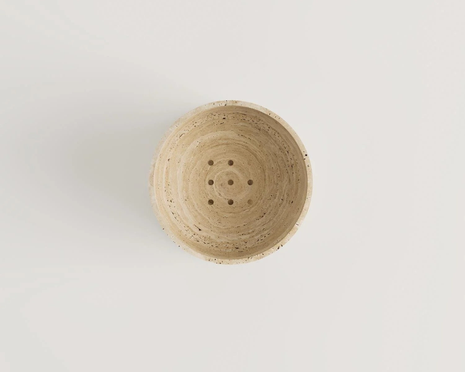 Overhead view of beige stone bowl with drainage holes