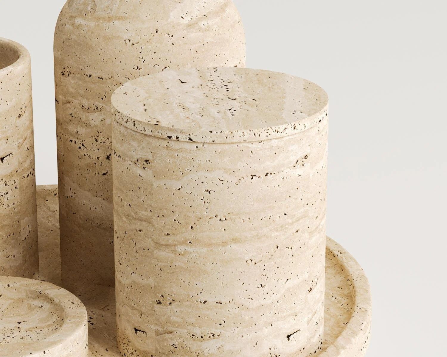 Close up view of beige travertine decor objects on white background