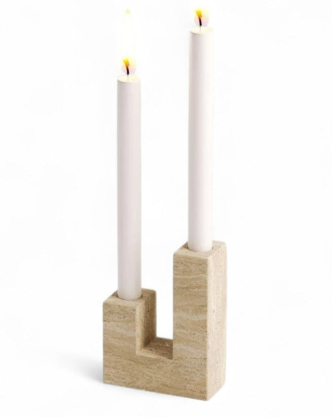 White candles burning in U-shaped travertine candlestick holder decor