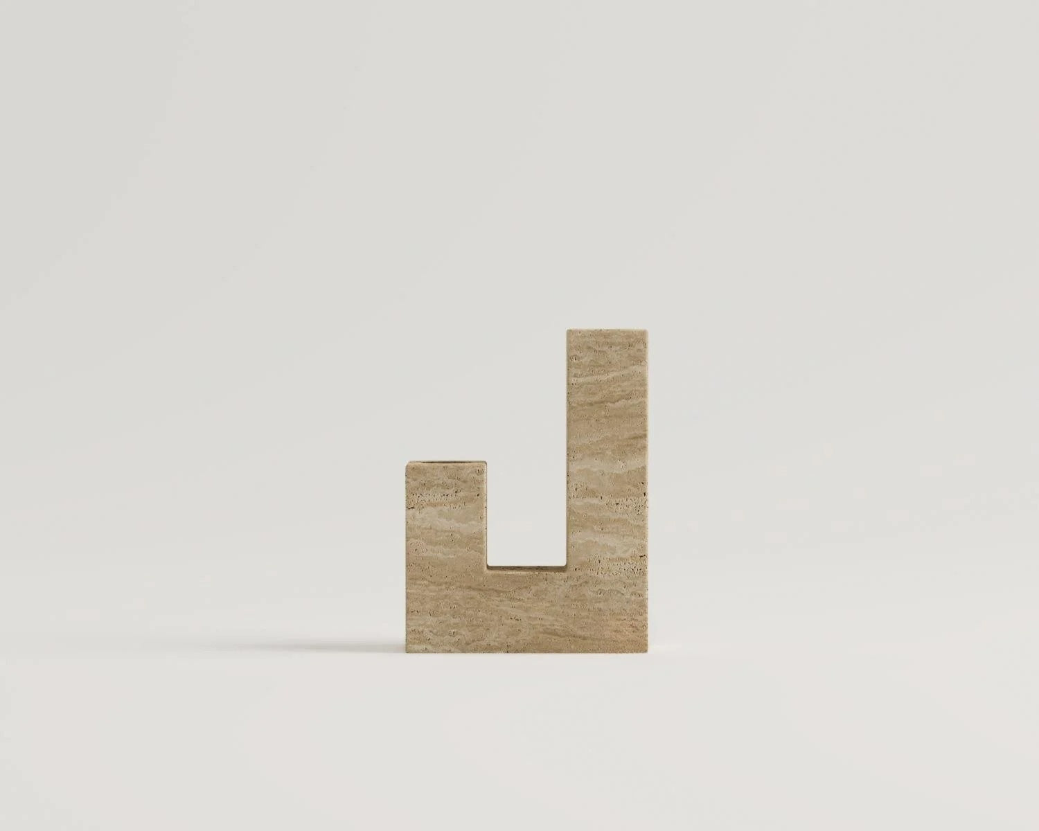 Travertine stone vase shaped like the letter L on white background