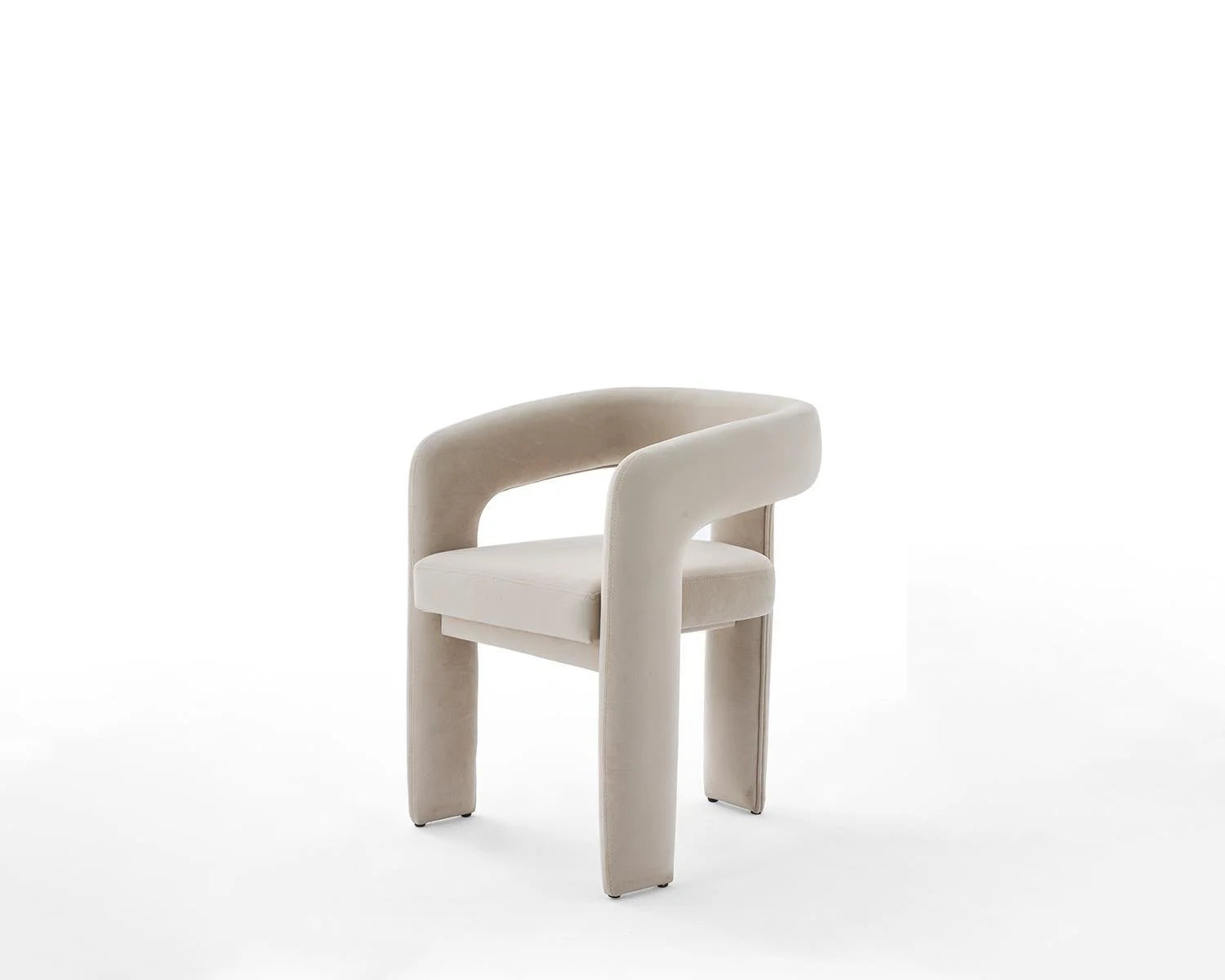 View of a beige velvet upholstered dining chair on white background. Beige velvet dining chair with curved back and armrests. Upholstered dining chair in beige velvet fabric. Modern beige velvet dining chair studio shot. Beige velvet dining chair furniture product photography.