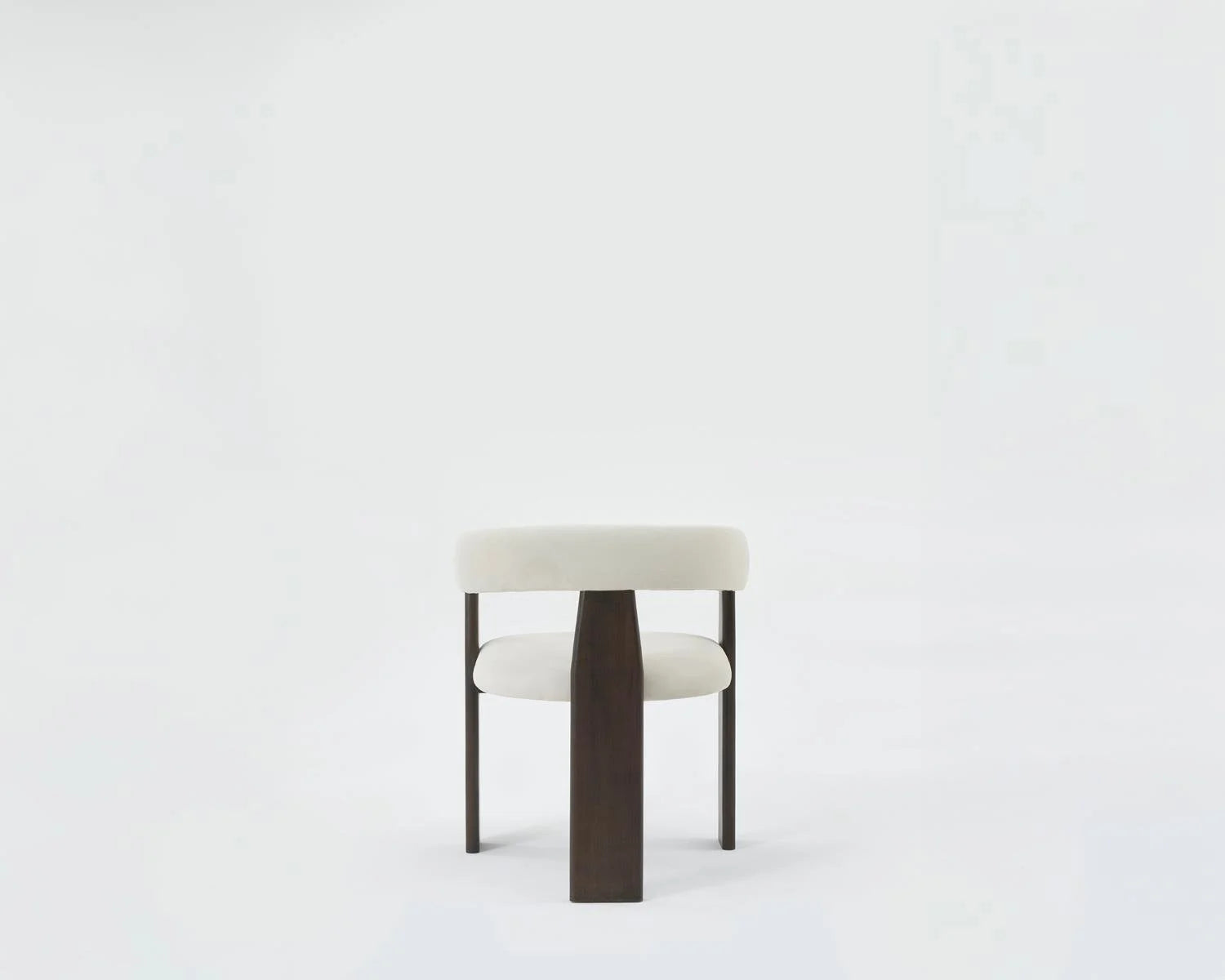 Studio shot of upholstered white velvet dining chair with dark wood frame. Modern minimalist dining chair with white upholstery. White velvet dining chair with dark wood frame on white background.