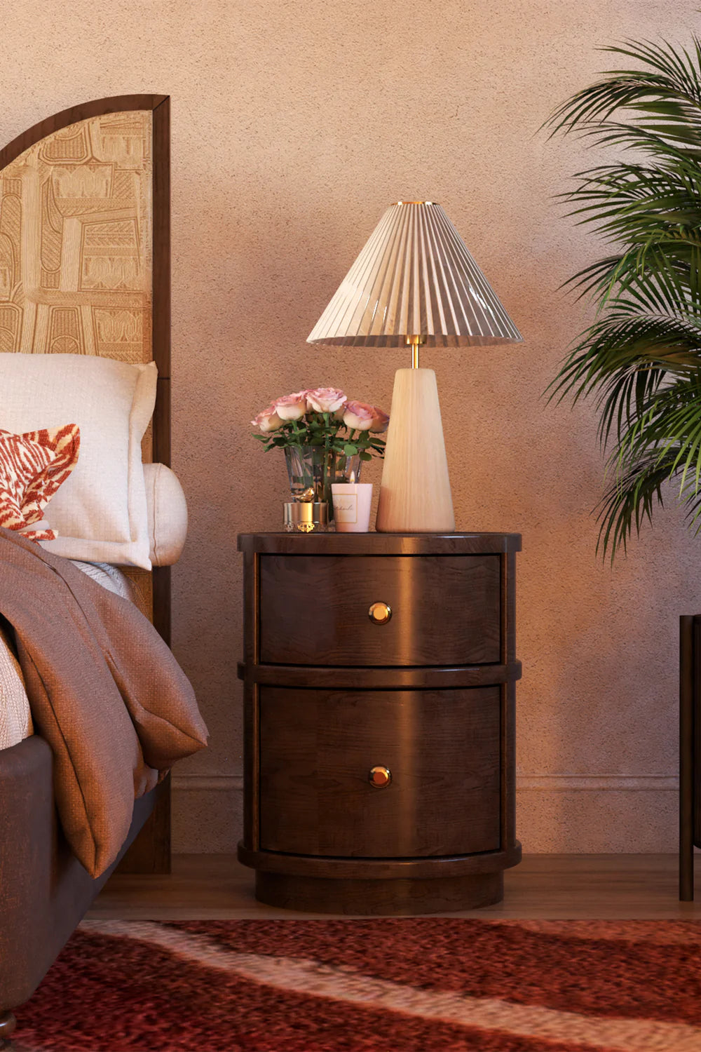 Wooden nightstand with lamp and flowers next to a bed in a bedroom setting