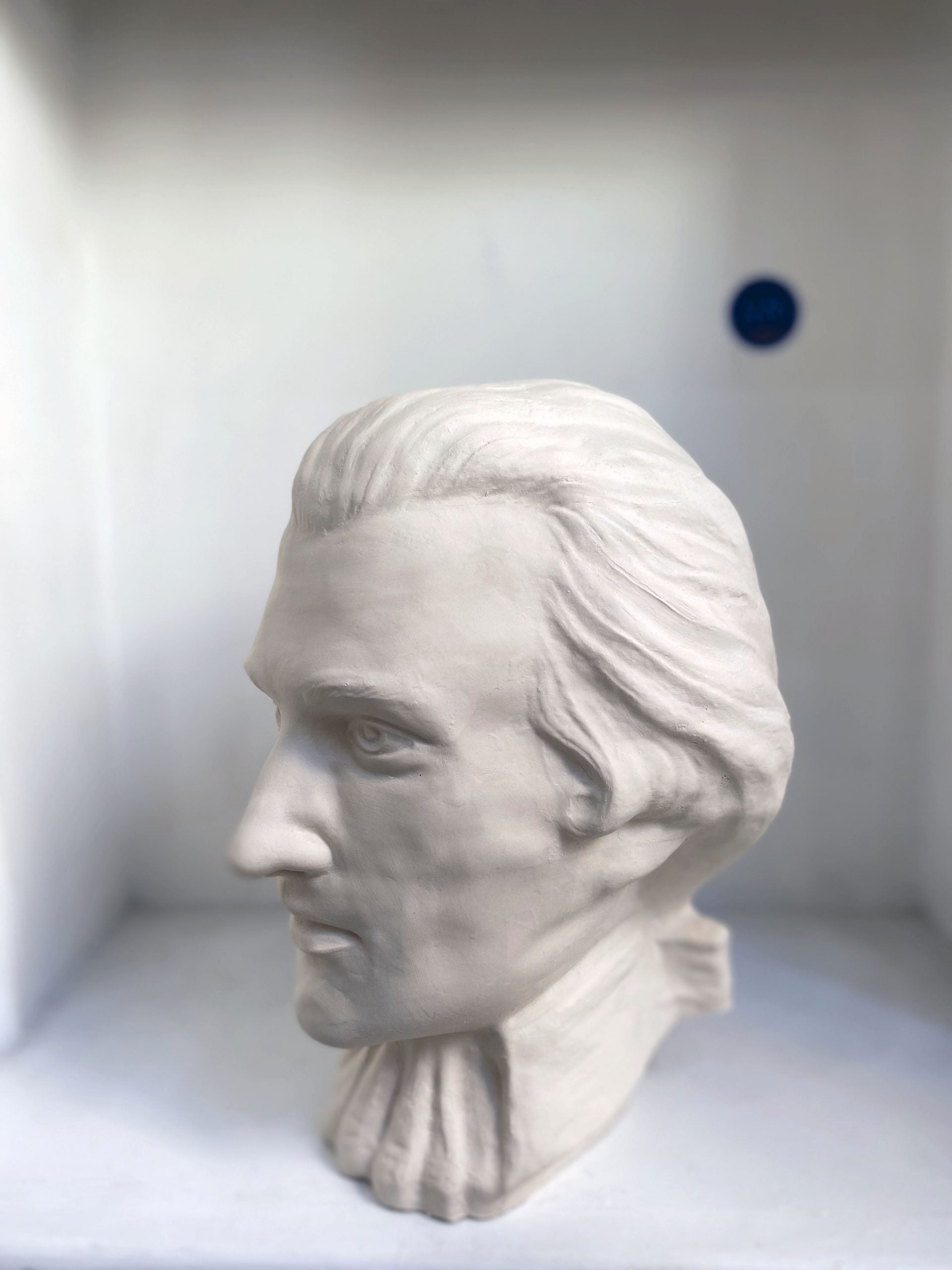 White plaster bust sculpture of a man's head in profile