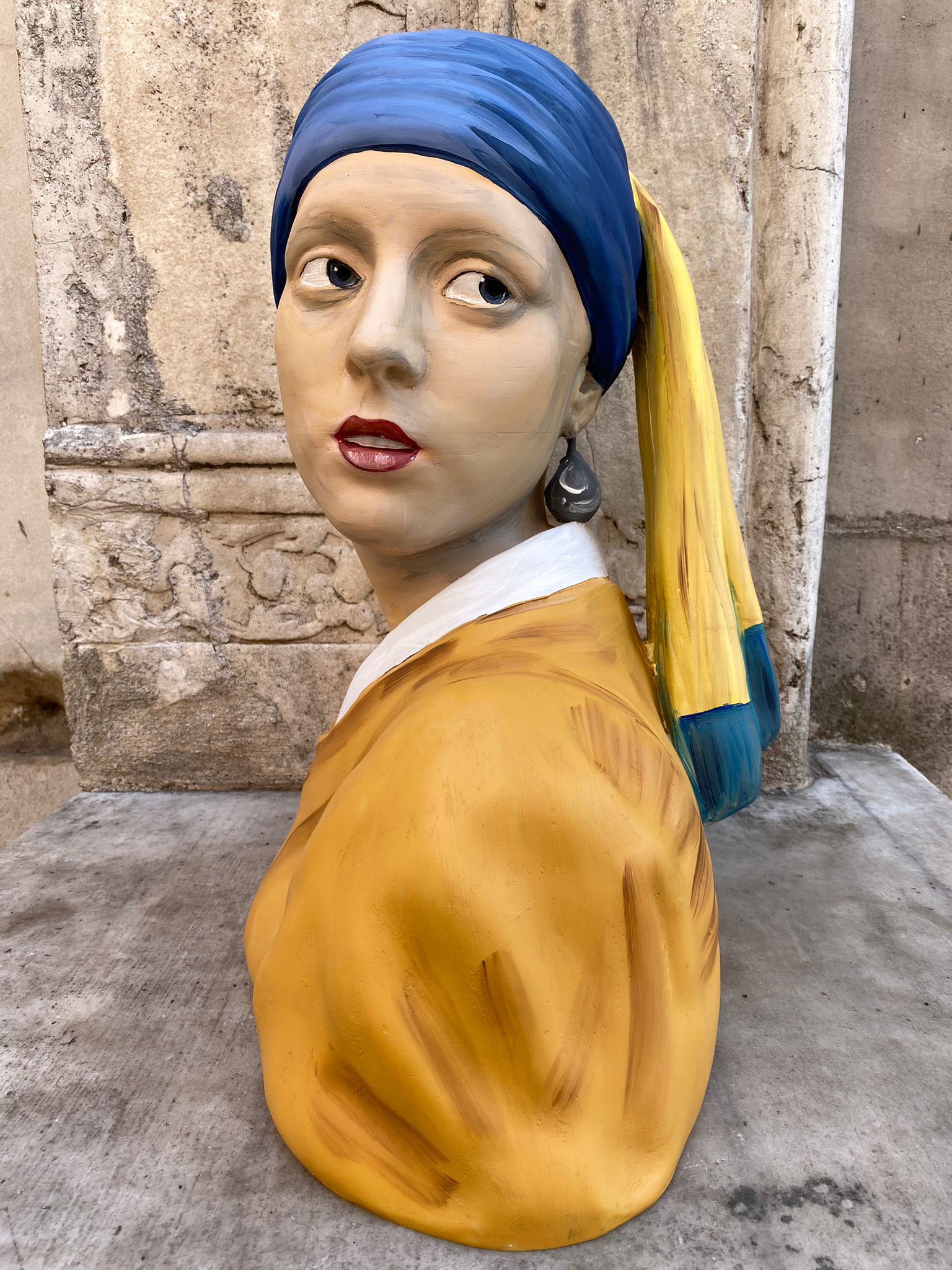 Close up view of Girl with a Pearl Earring sculpture bust on stone ledge. 