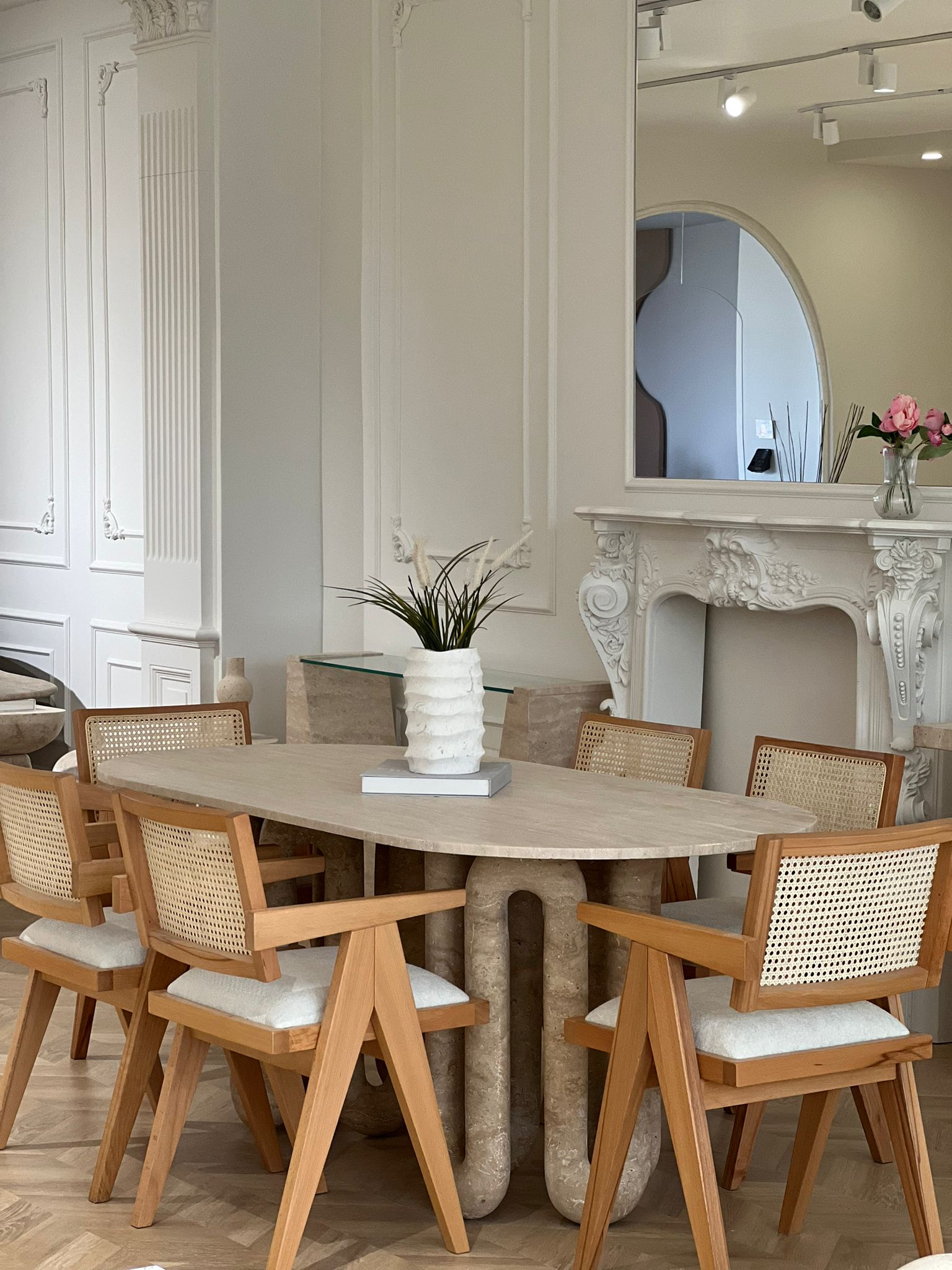 Luzione Celestia Travertine Dining Table with cane back chairs in a modern dining room interior.