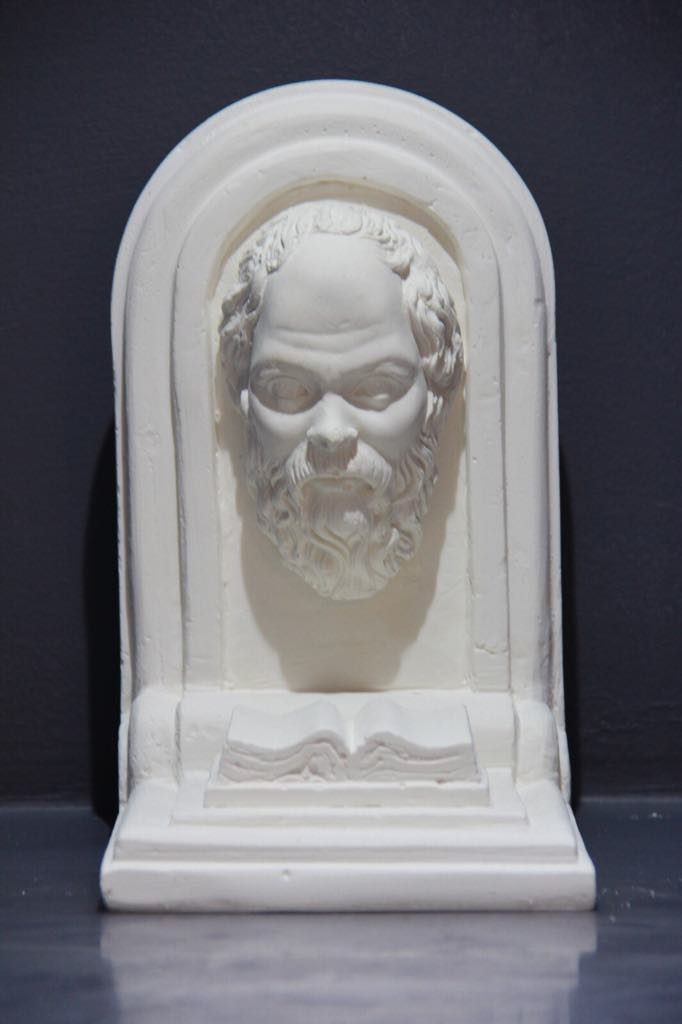 White plaster sculpture of bearded man's head above open book