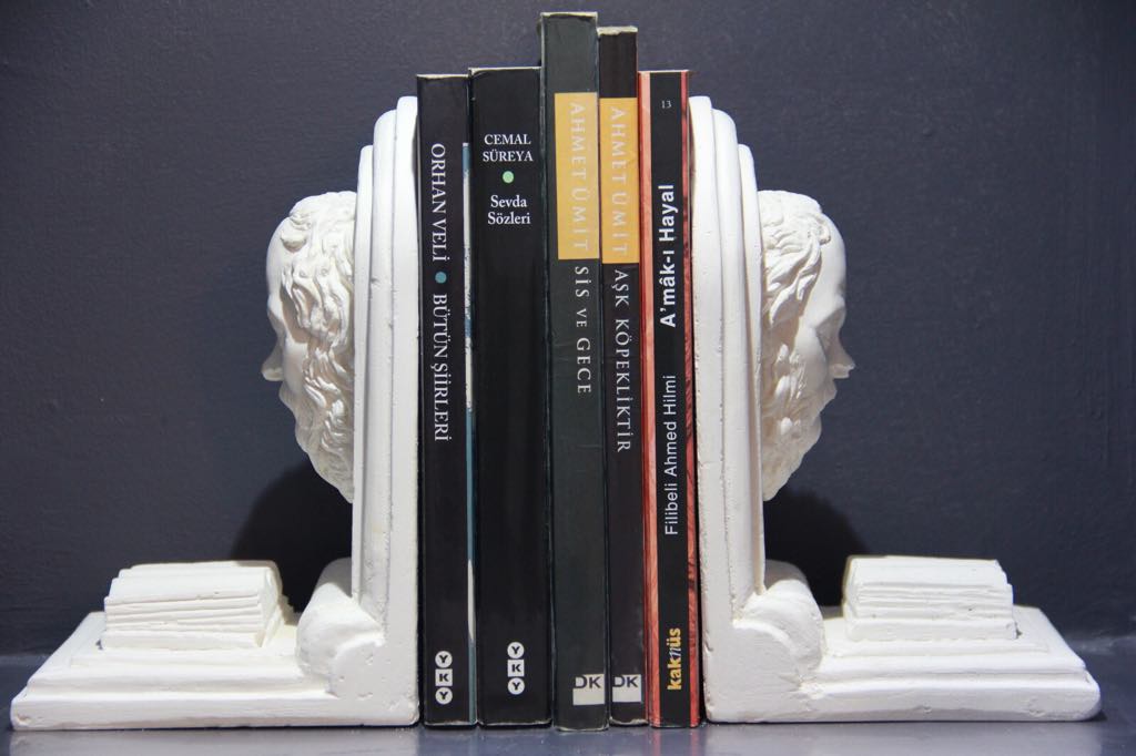 White plaster bust bookends holding six books on shelf