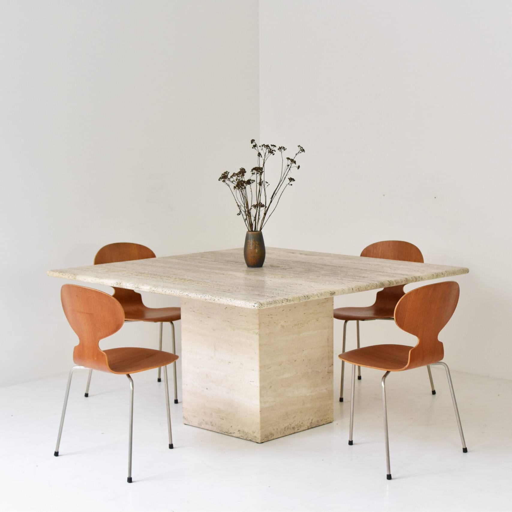 Modern square travertine dining table with wooden chairs in a minimalist setting. Perfect contemporary furniture for dining room decor