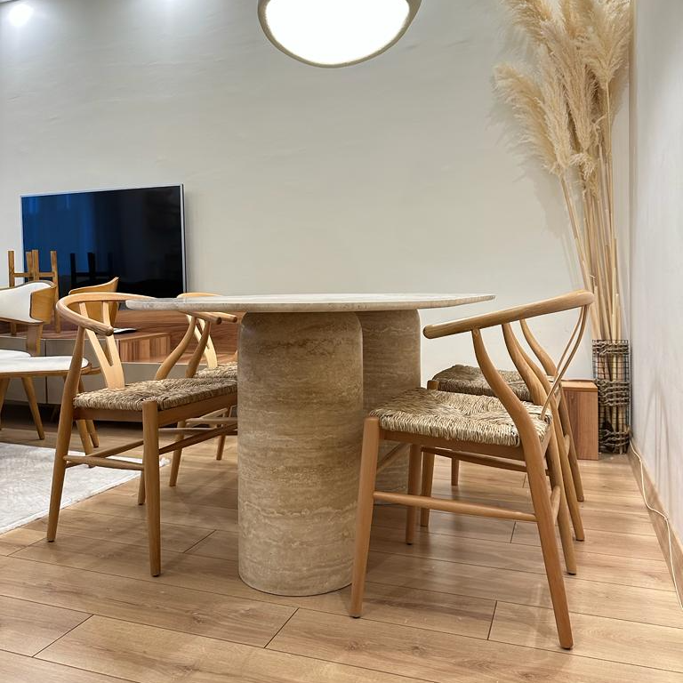 Modern dining room set with a round Luzione travertine dining table featuring a double pedestal base and stylish wishbone chairs with woven seats