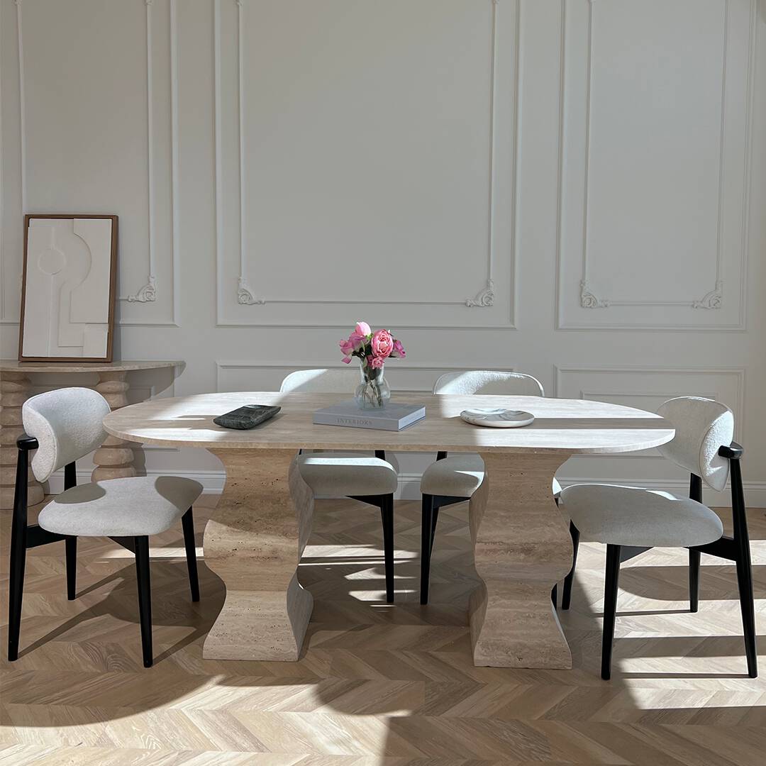Modern dining room featuring a Luzione Designer Travertine Dining Table with pedestal base and upholstered chairs, minimalist decor, and herringbone wood floors