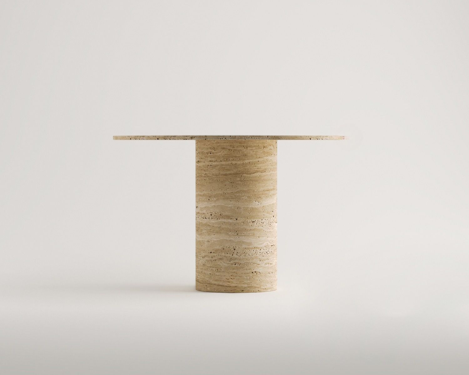 Minimalist studio shot of the Bhūmi Single Cylinder Base Round Travertine Dining Table by Luzione; a modern stone side table with a cylindrical base