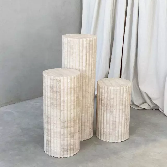 Three Luzione travertine plinths of varying heights create a modern, minimalist display. Perfect as side tables or pedestals for art and plants.