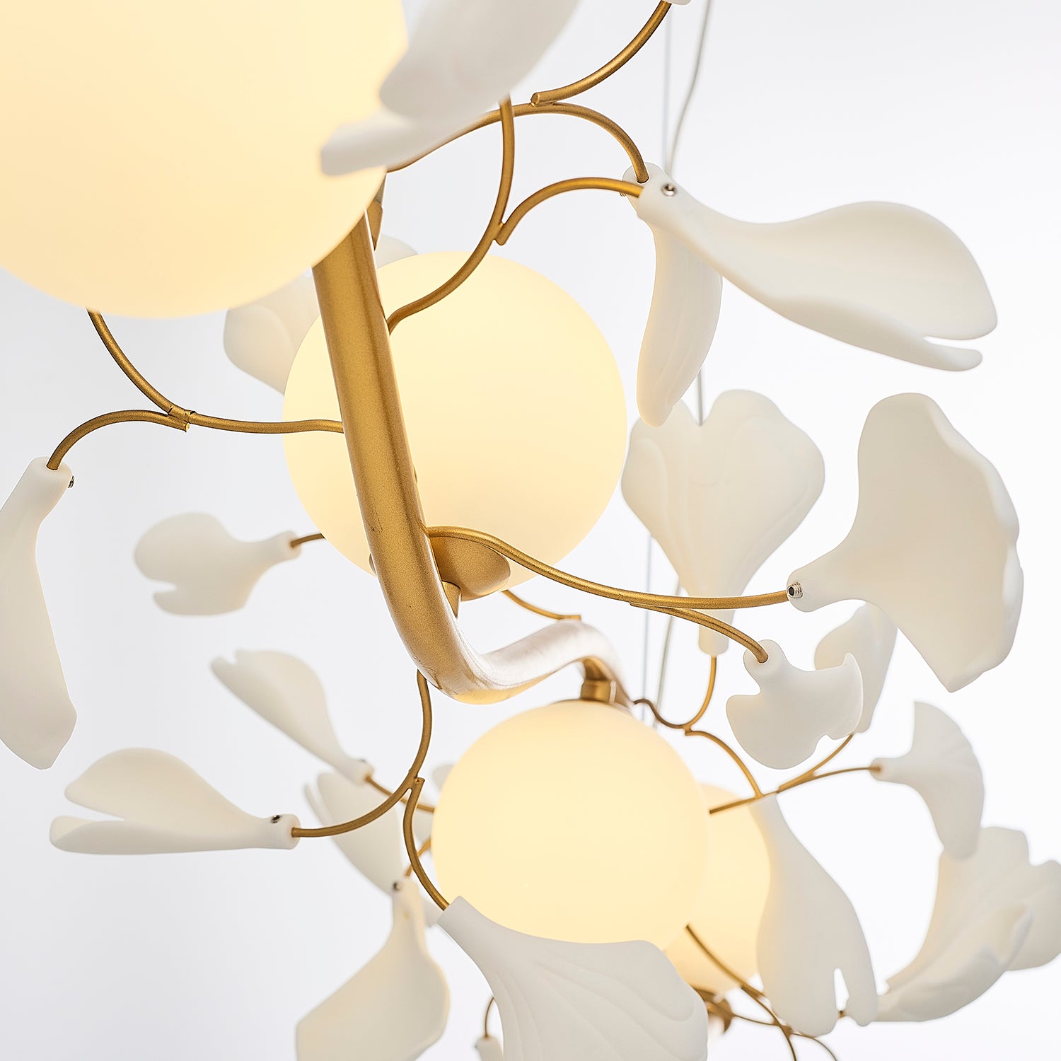 Lighting fixture with gold branches, white globes, and leaves.