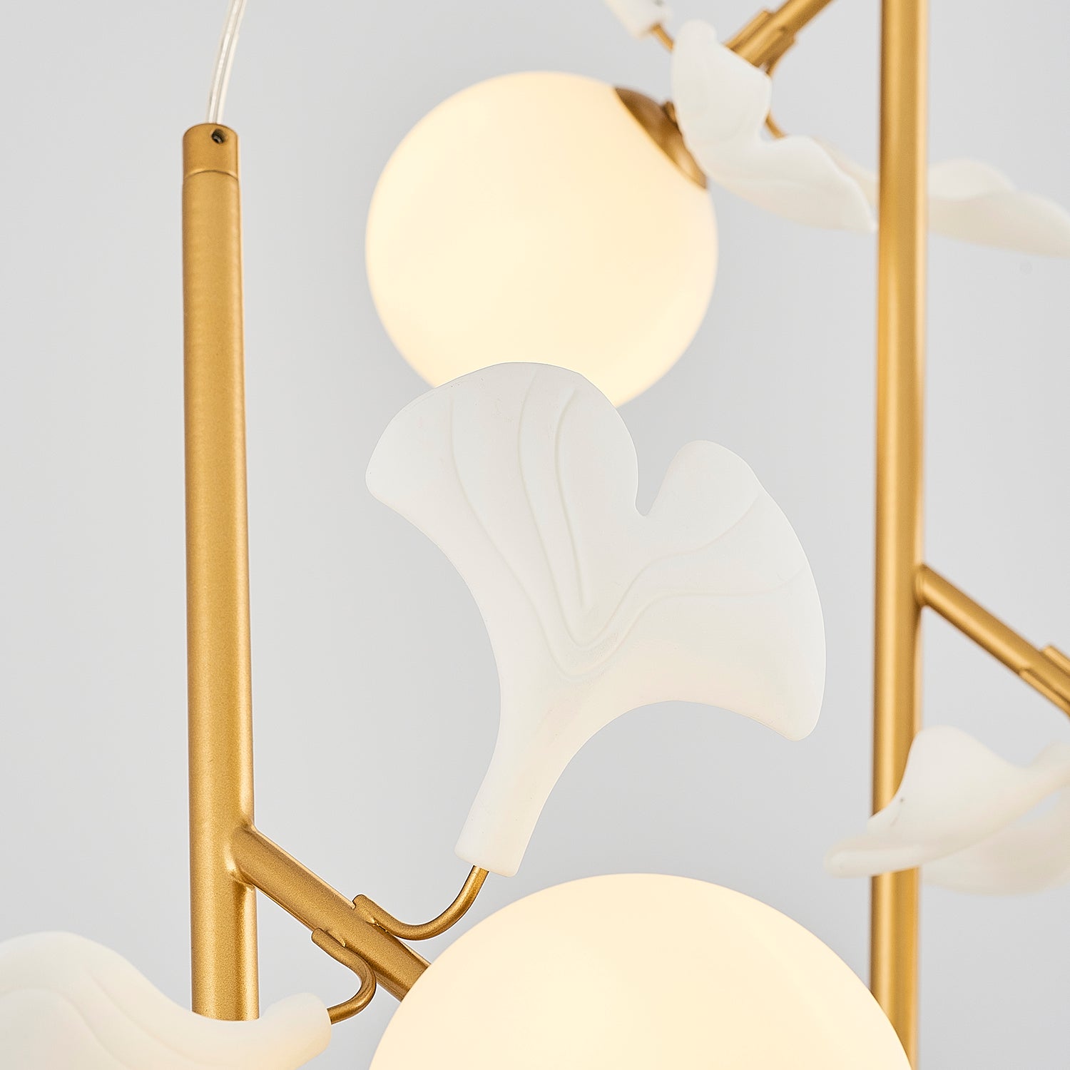 Close up lighting fixture gold metal white glass globes leaves