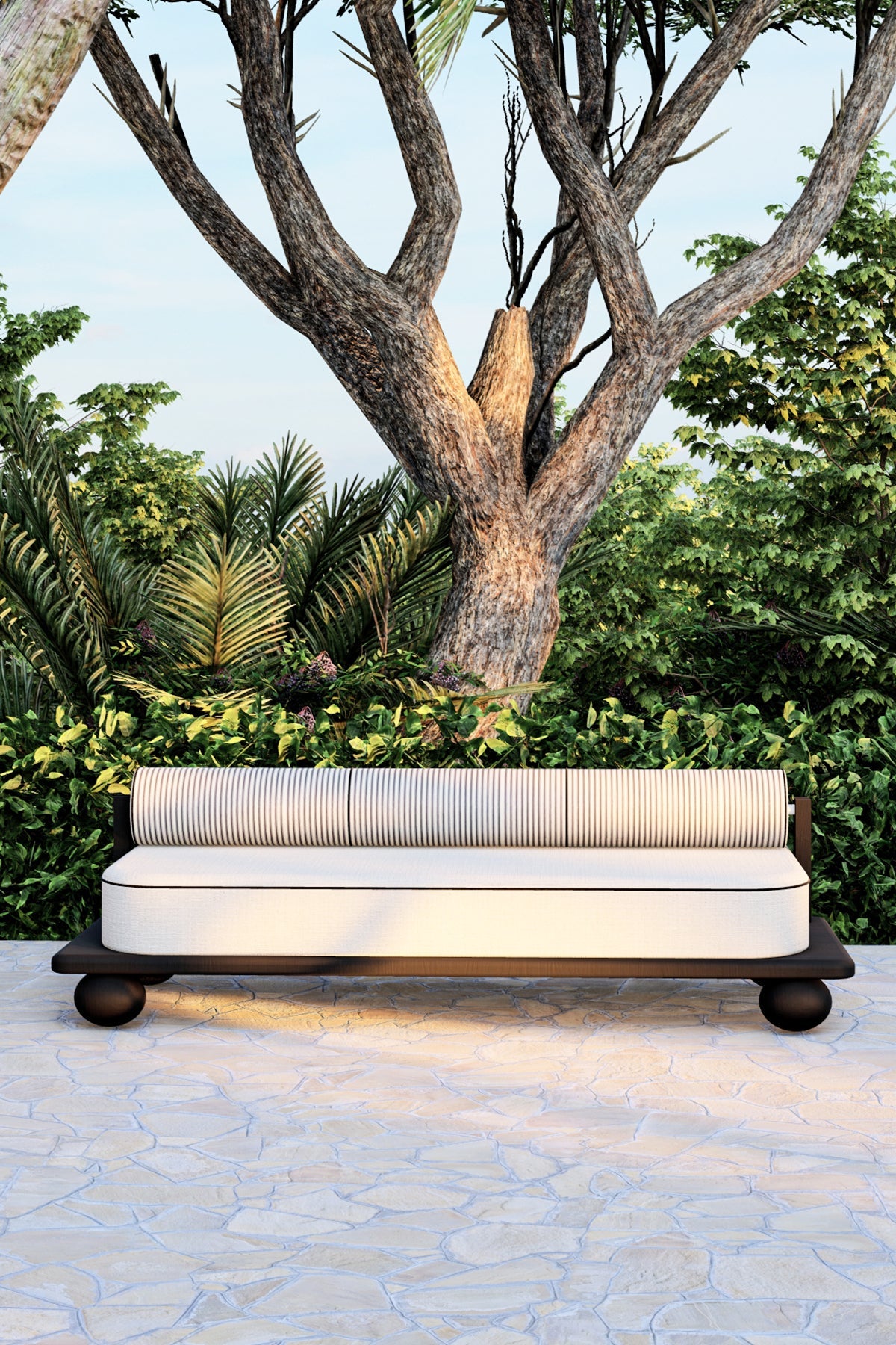 Outdoor sofa with striped cushion on stone patio near trees