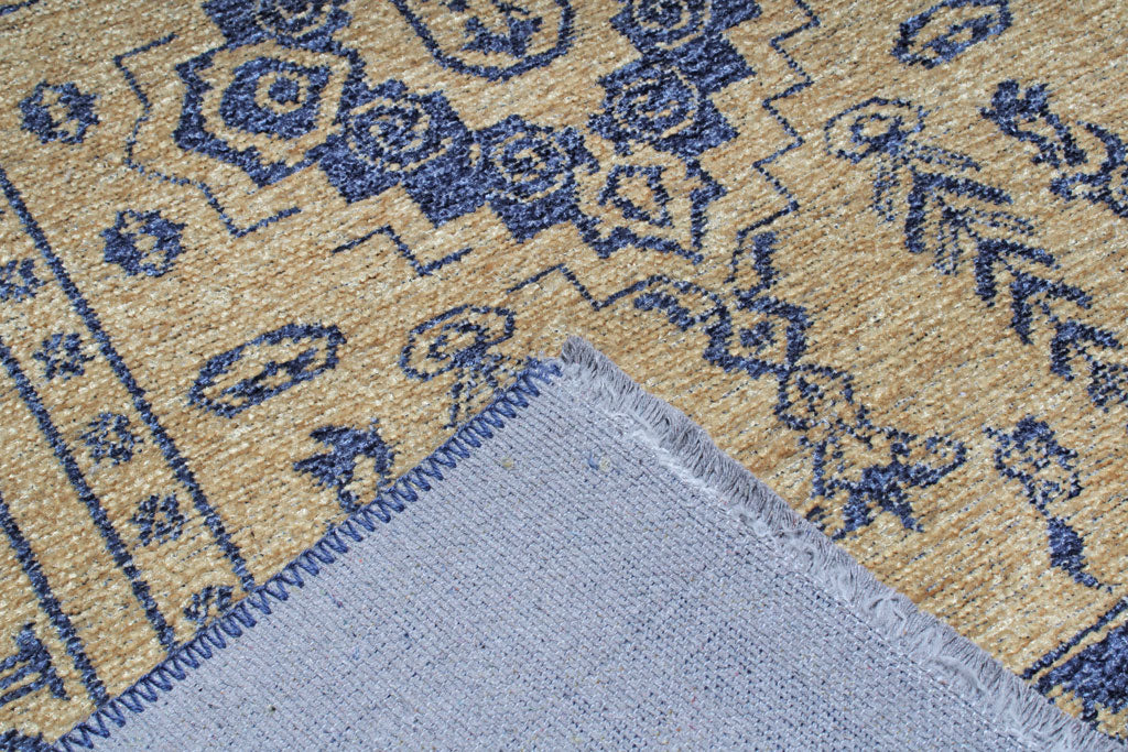 Close up view of tan and blue patterned rug showing backing