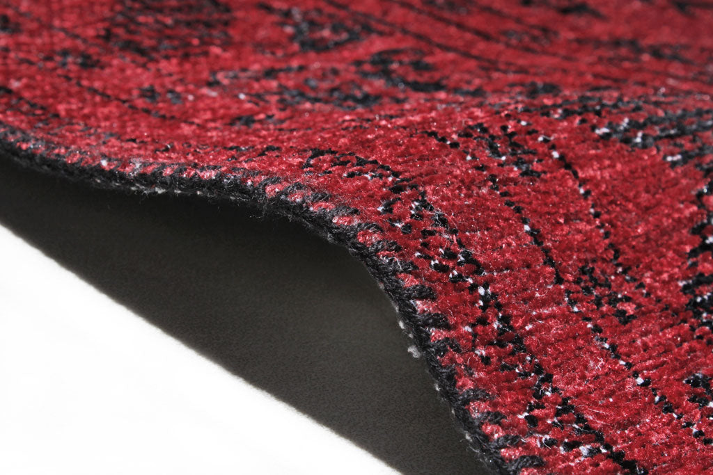 Close up of red and black patterned rug edge showing backing