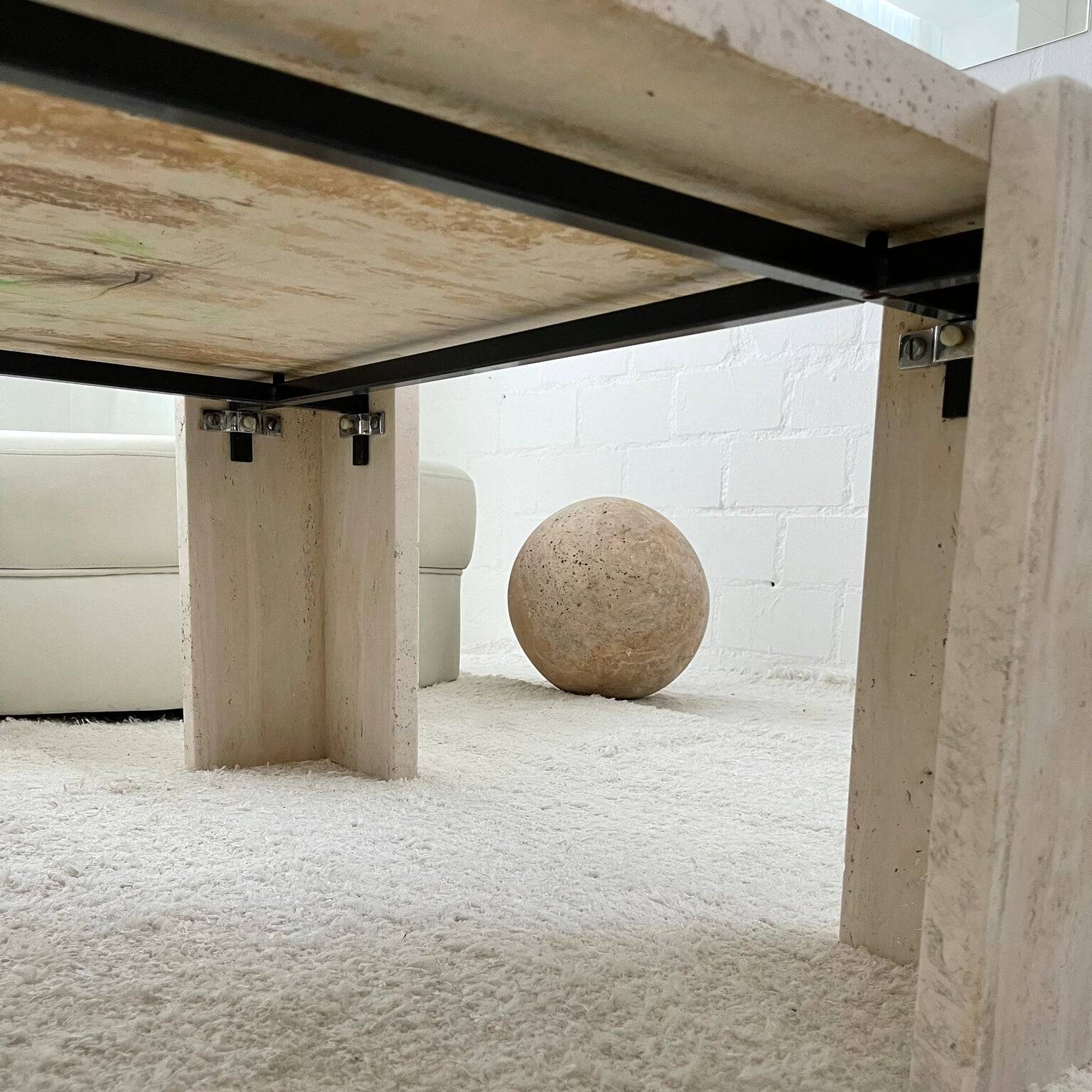 A low-angle shot of a Luzione travertine coffee table, highlighting its stone top, base, and sleek metal frame. Perfect for modern living spaces