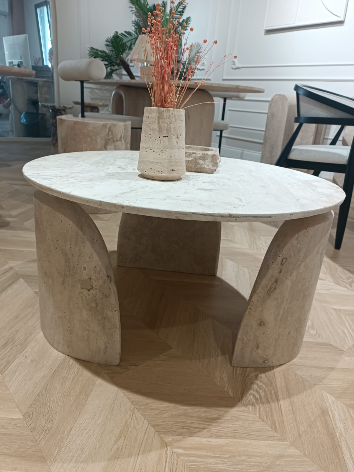 Luzione 631 travertine coffee table with curved legs and a travertine vase holding dried orange flowers, set in a modern living room