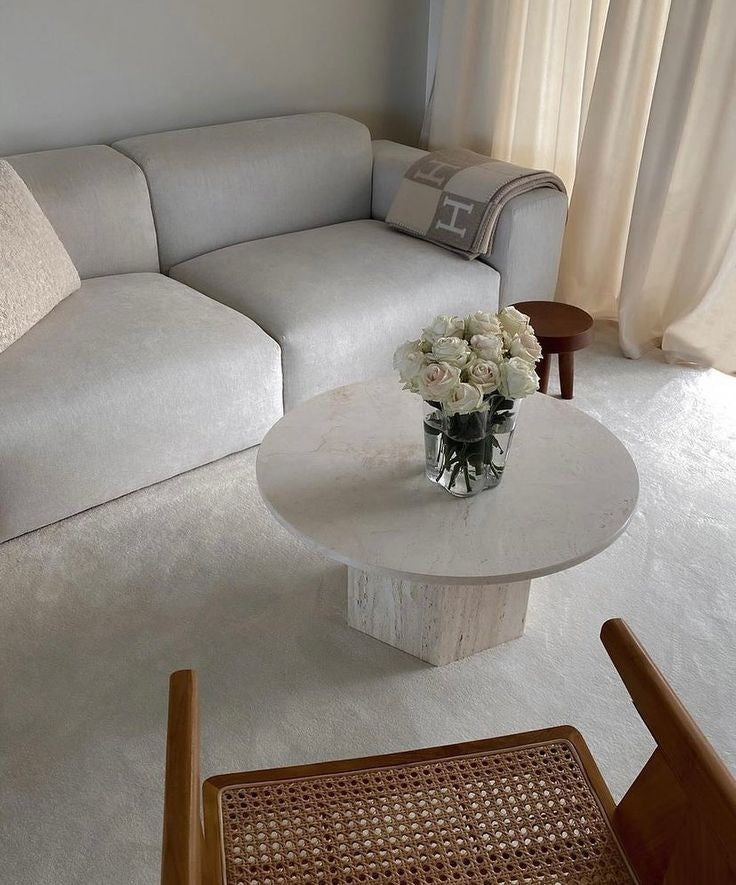 Modern living room featuring a Luzione modular sofa, marble coffee table, and woven chair, showcasing minimalist interior design and contemporary furniture