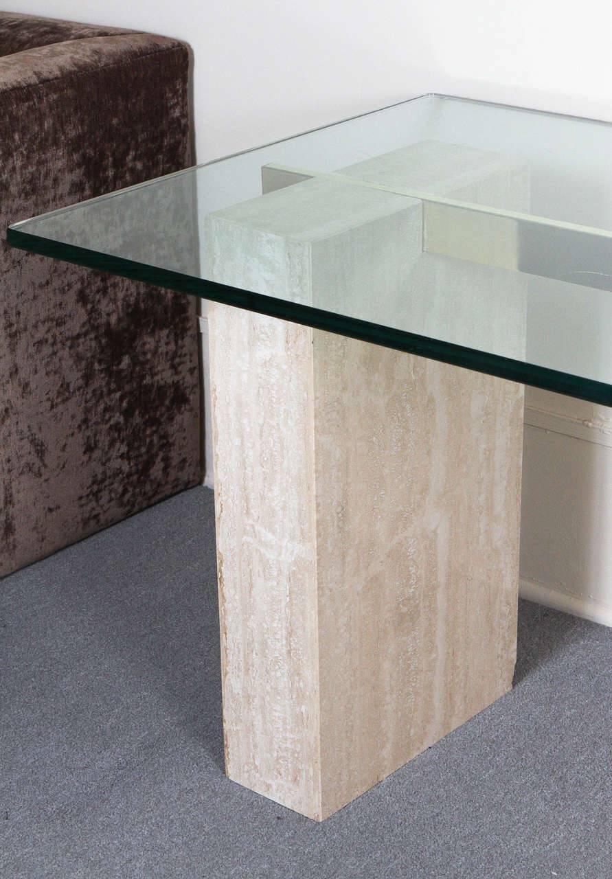Close-up of Luzione travertine table with glass top. Modern living/dining room furniture with stone base and sleek design