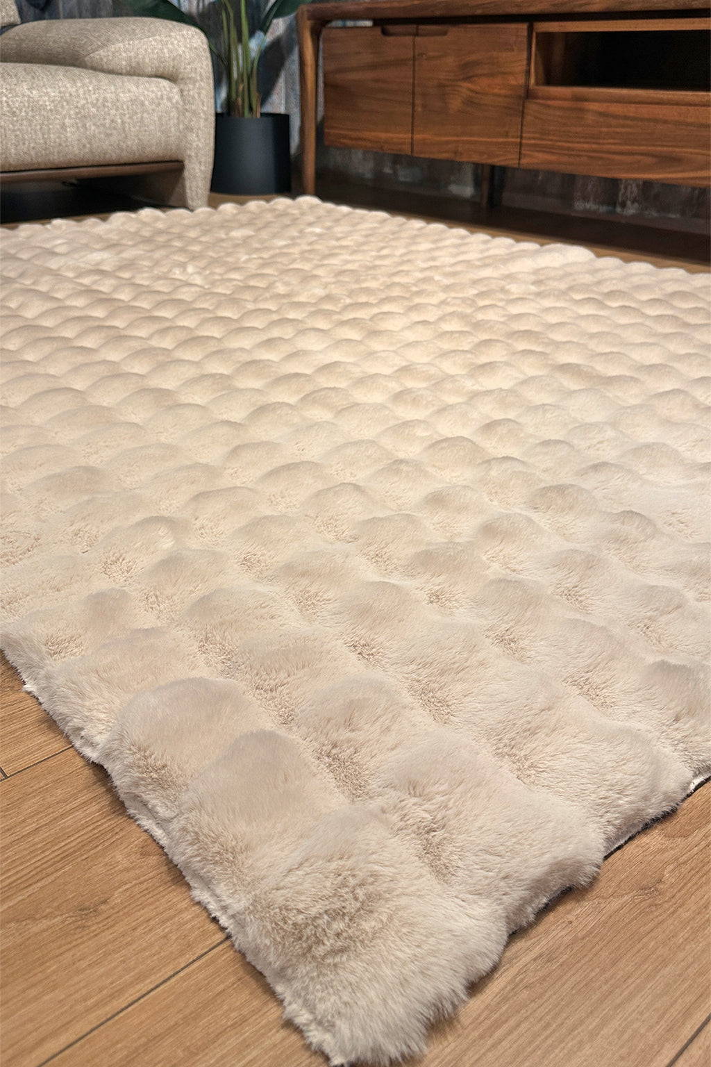 Cream faux fur rug with textured squares on wood floor