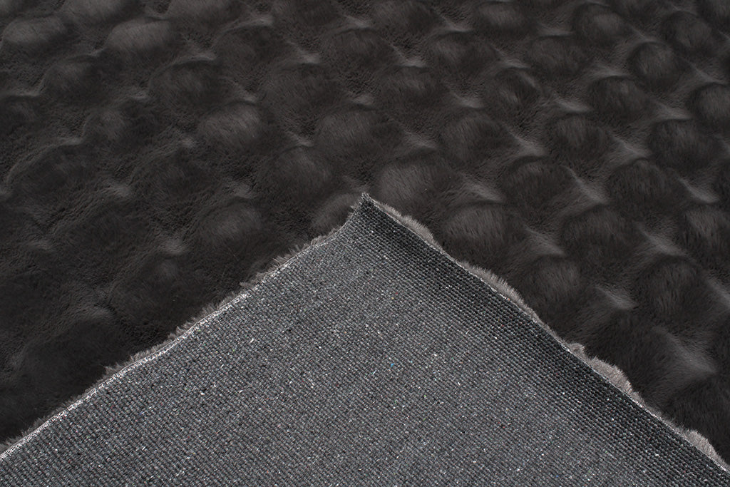 Close up view of dark gray textured faux fur rug showing backing