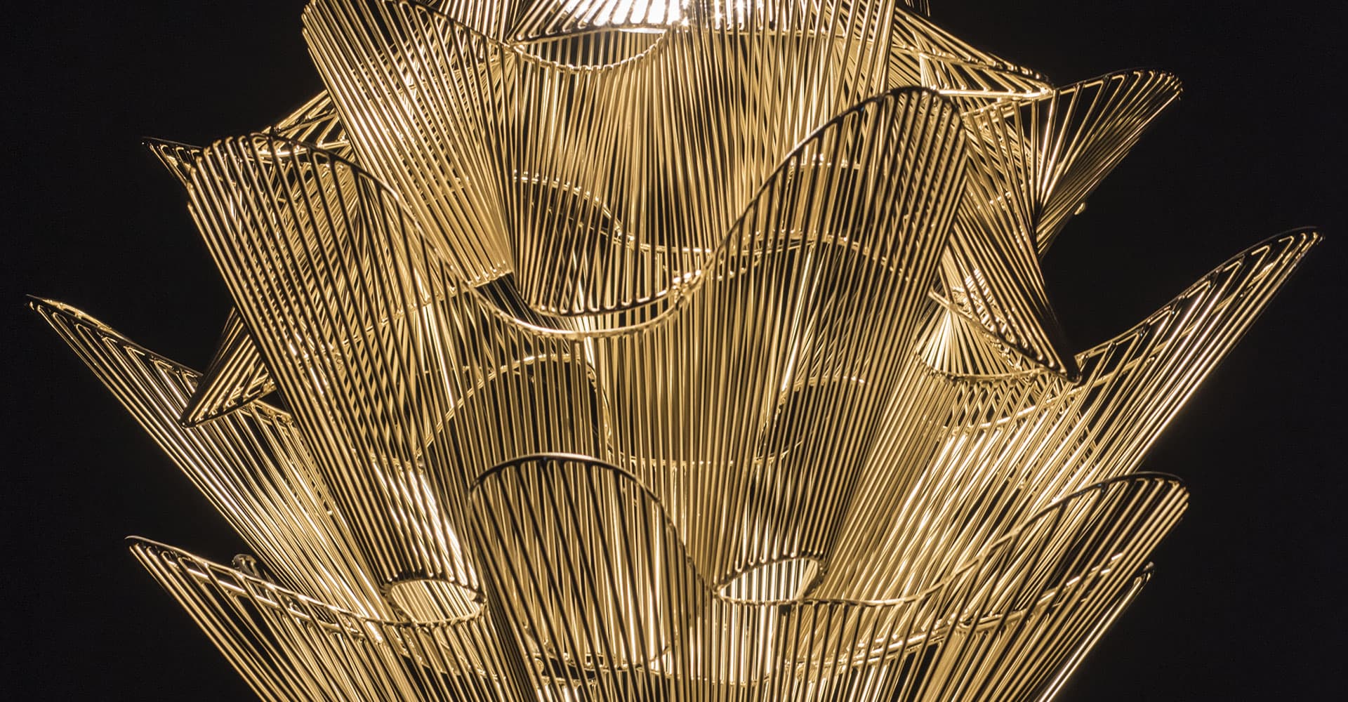Close up of gold wire lighting fixture against black background