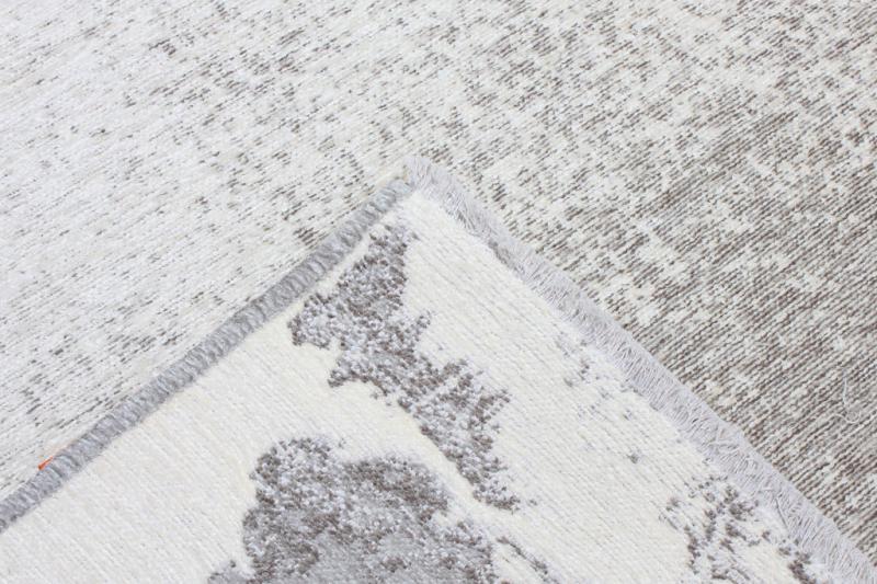 Close up view of white and gray patterned rug corner and backing.